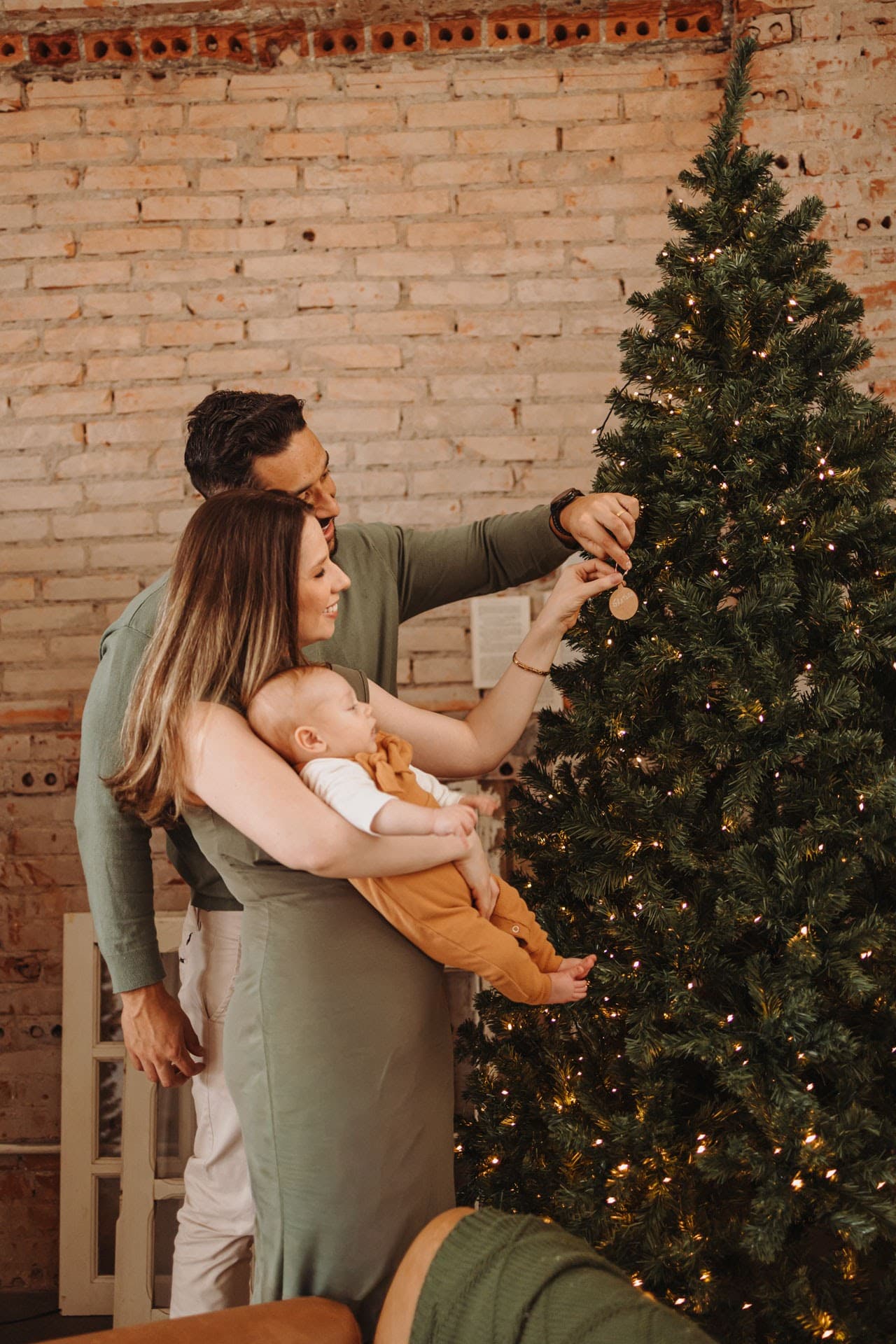 Família decorando a árvore de natal com bebê