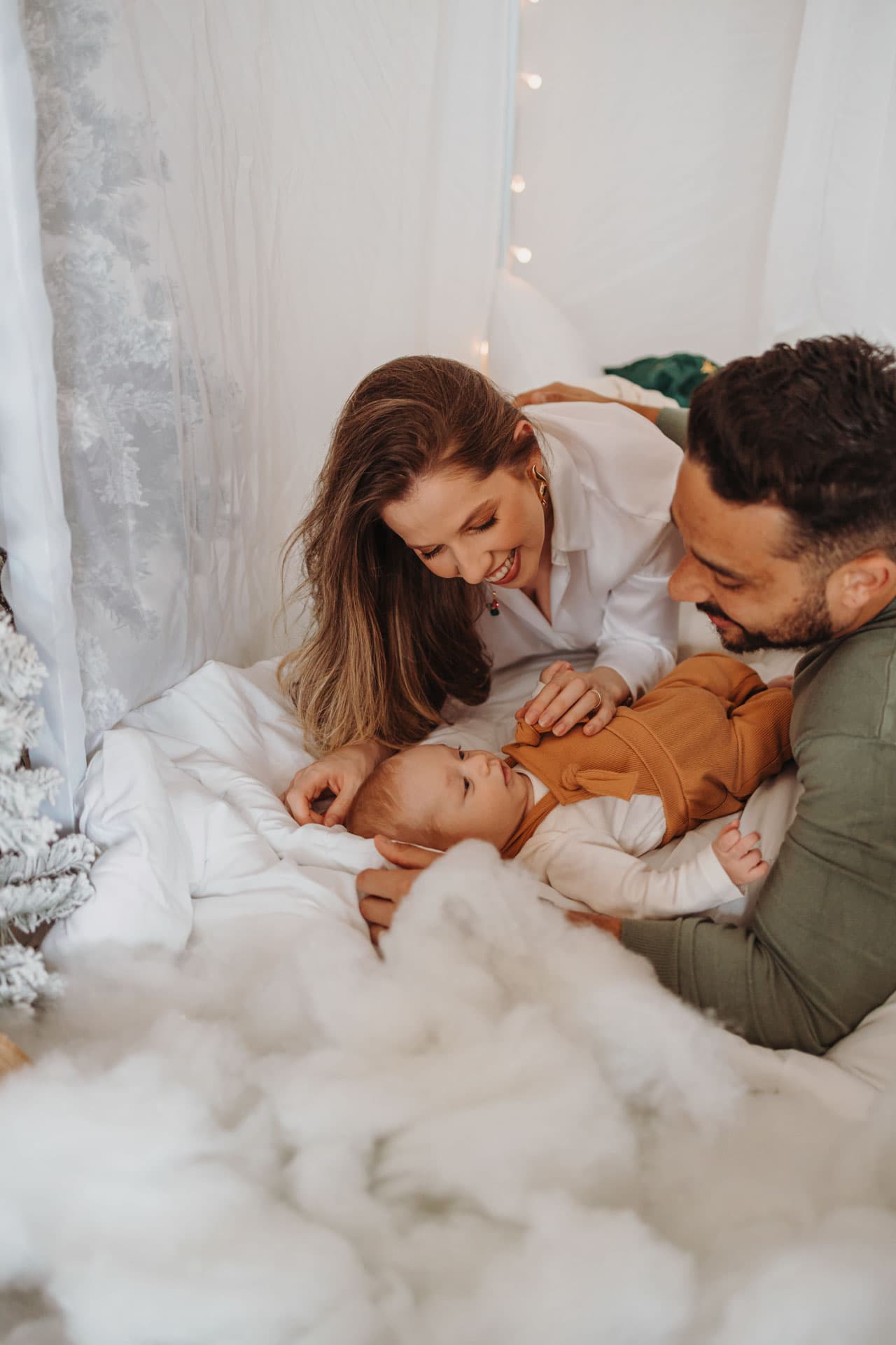 Família deitada e brincando carinhosamente com o bebê